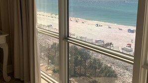 A room with a large window overlooking a beach.
