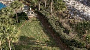 A beach resort with a pool, palm trees, and a fenced area with beach chairs.
