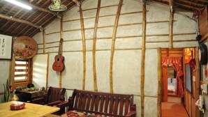 Una habitación tradicional con paredes de bambú, una mesa de madera, un banco y una guitarra.
