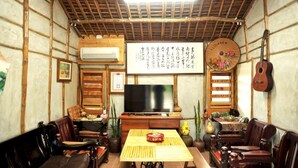 Una habitación tradicional japonesa con suelo de tatami, techo de madera bajo y un televisor sobre un soporte de madera.