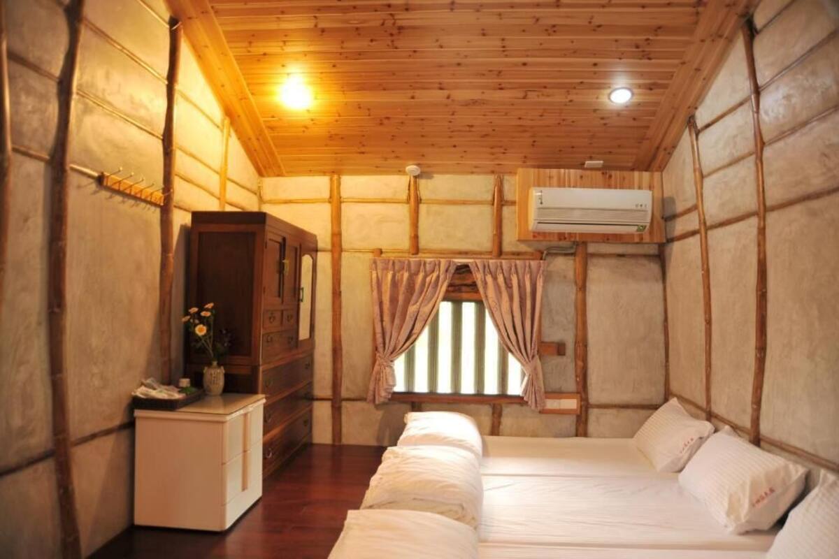 A compact room with a bed, a small desk, a wardrobe, and an air conditioning unit.