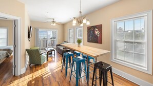 A spacious kitchen with a long wooden table, blue bar stools, and a ceiling fan.