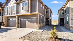 A two-story house with a garage, stone foundation, and a small tree in the driveway. - *NEW w/ VIEWS* | Modern Mtn. Townhome minutes from RMNP, WP, & Granby Ranch! (Granby)