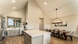 A modern kitchen with a large island, stainless steel appliances, and a dining area with a wooden table and chairs. - *NEW w/ VIEWS* | Modern Mtn. Townhome minutes from RMNP, WP, & Granby Ranch! (Granby)