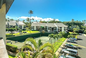 Un hôtel composé de plusieurs bâtiments, doté d’un court de tennis et d’un parking où sont stationnées plusieurs voitures.