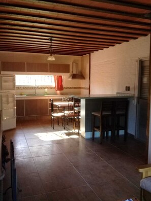 Een keuken met een houten plafond, een eethoek met stoelen en een bargedeelte.