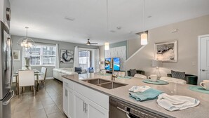 A modern kitchen with a central island, built-in appliances, and a dining area with a white table and chairs.