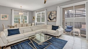 A modern living room with a sectional sofa, a glass coffee table, and a ceiling fan.