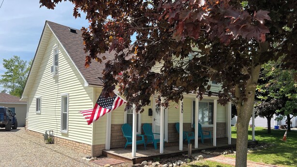 Une maison avec un porche, un drapeau et une allée gravillonnée.