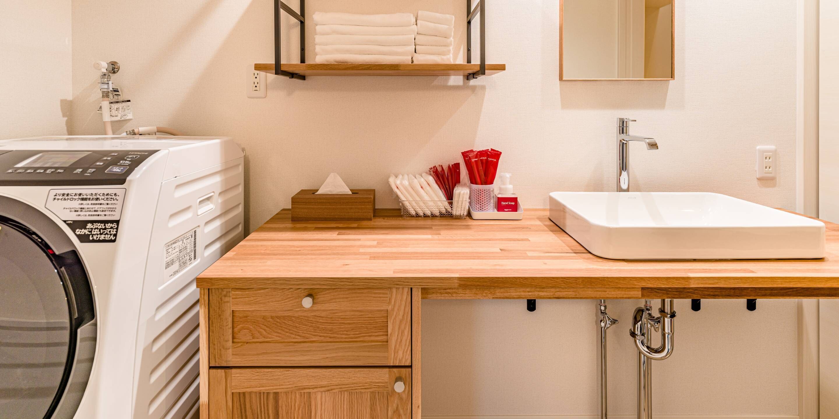 A laundry area with a washing machine, a wooden counter, a sink, and a towel rack.