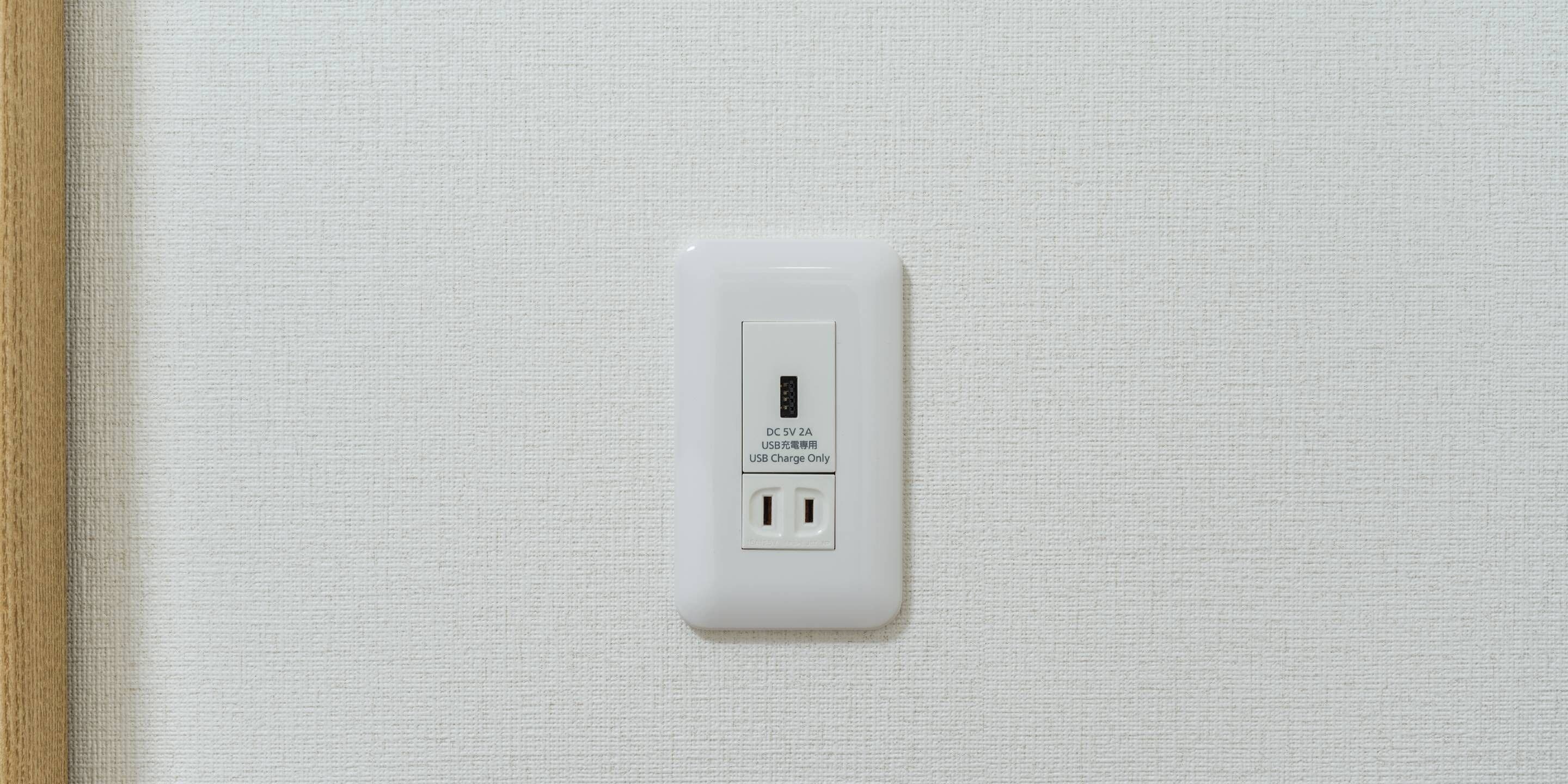 A white electrical outlet with a USB port on a textured wall.