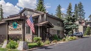 A two-story building with a stone facade, a wooden deck, and a flag. - Chamonix #62 Bldg. D (Mammoth Lakes)