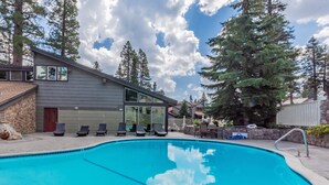 A modern building with a swimming pool, lounge chairs, and a stone facade. - Chamonix #62 Bldg. D (Mammoth Lakes)