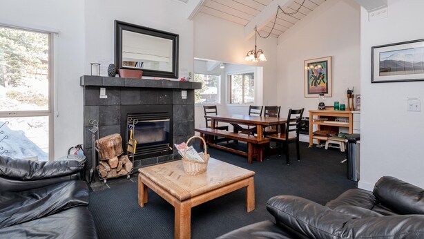 A cozy living room with a fireplace, leather sofas, a wooden coffee table, and a dining area with wooden tables and chairs. - Chamonix #62 Bldg. D (Mammoth Lakes)