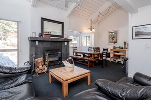 A cozy living room with a fireplace, leather sofas, a wooden coffee table, and a dining area with wooden tables and chairs. - Chamonix #62 Bldg. D (Mammoth Lakes)