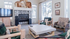 Ein gemütliches Wohnzimmer mit Kamin aus Stein, Holzmöbeln und einem Fernseher.