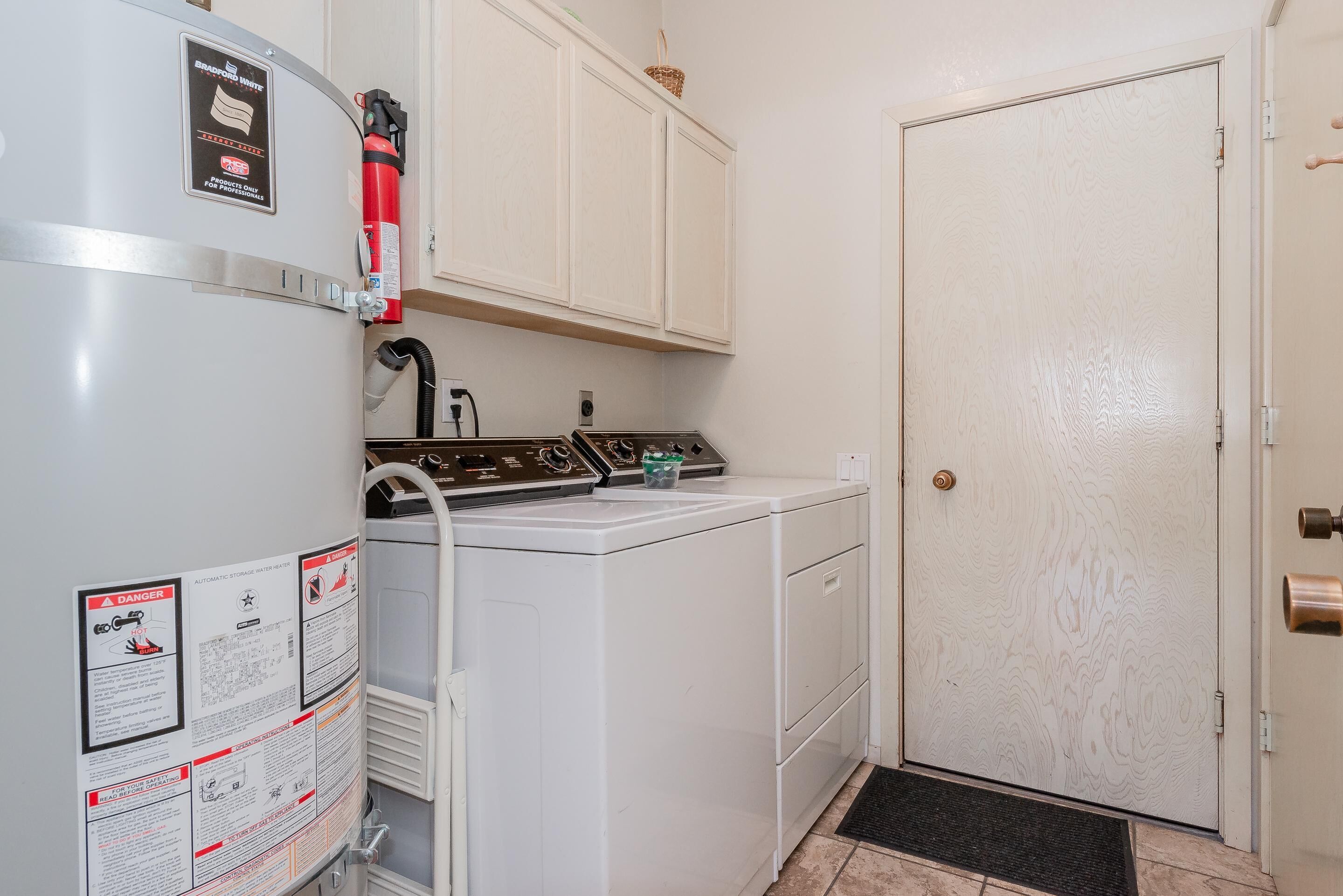 A laundry room with a washing machine, dryer, and a fire extinguisher mounted on the wall.