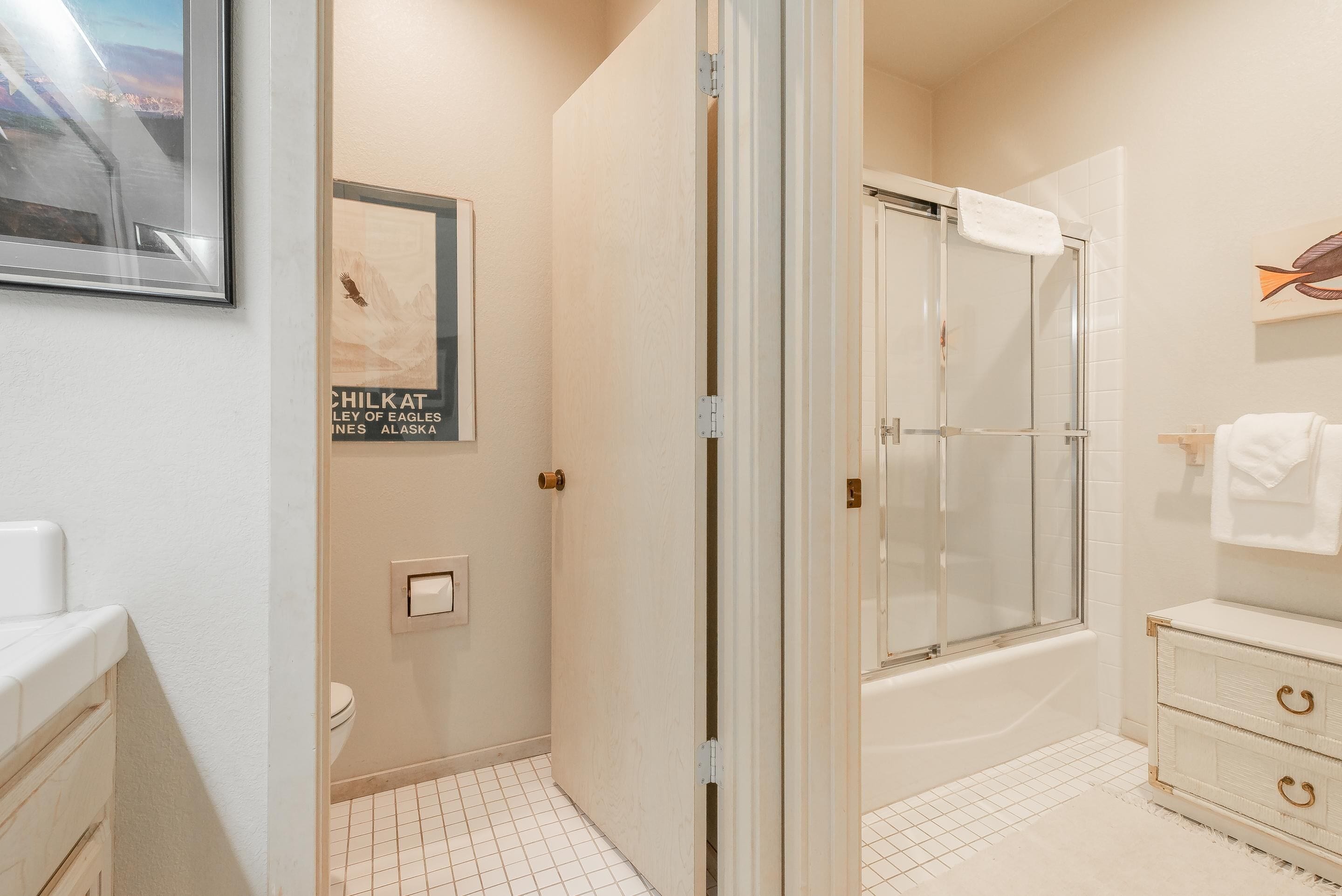 A bathroom with a glass-enclosed shower, a toilet, and a sink.
