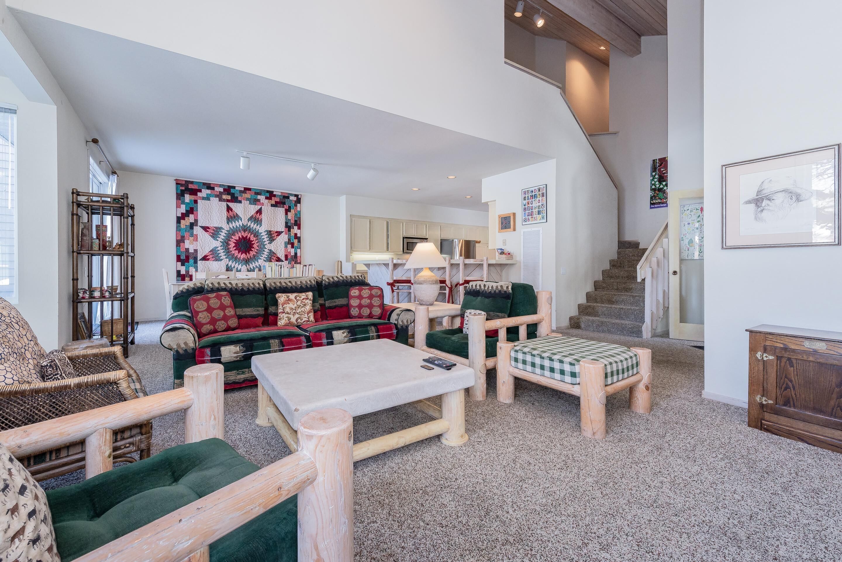 Un salon spacieux avec un grand canapé, une table basse et un escalier menant à un niveau supérieur.