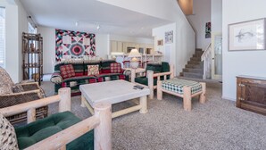 Ein geräumiges Wohnzimmer mit einer großen Couch, einem Couchtisch und einer Treppe, die in eine obere Ebene führt.