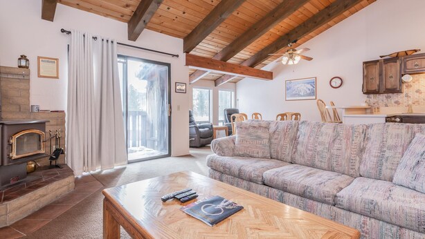 Una sala de estar acogedora con chimenea, un sofá, una mesa de centro y una zona de cocina.