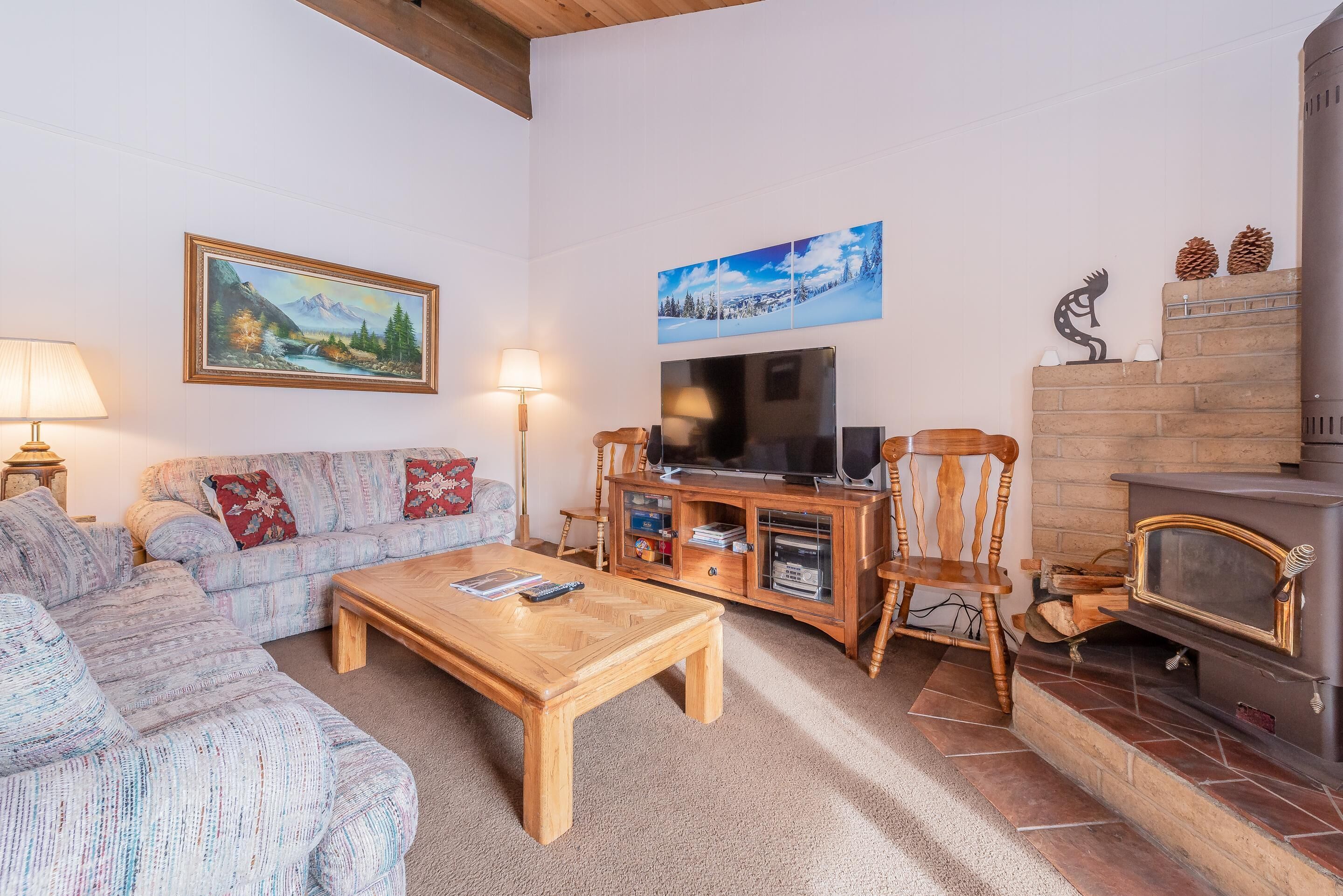 A living room with a sofa, coffee table, TV, fireplace, and artwork on the walls.