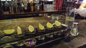 A bar counter with a variety of bottles and glasses, including a lime wedge garnish on a glass. - Suzhou Blue Gate Hostel (Suzhou)