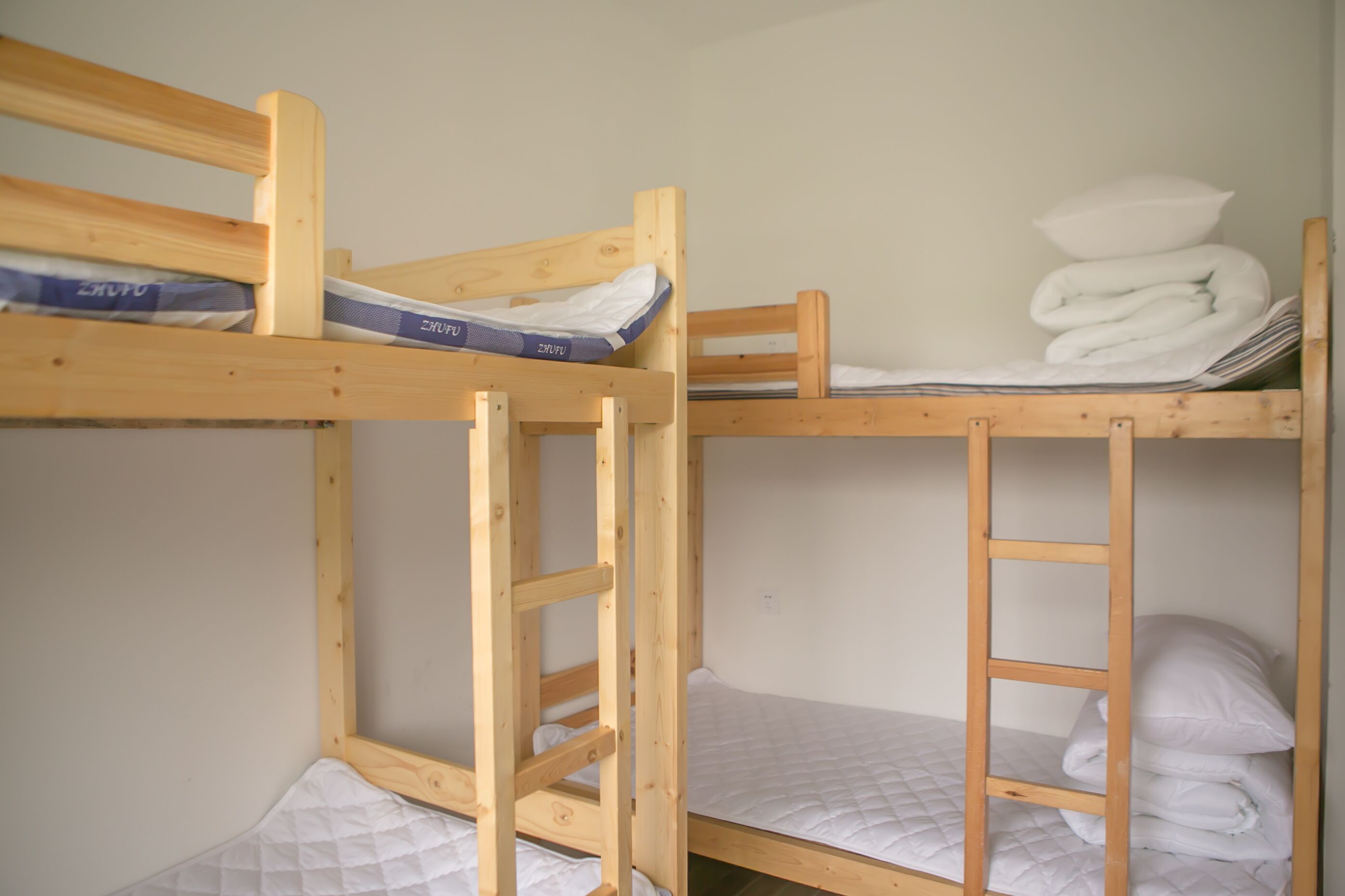 A bunk bed with wooden frames, a mattress, and a pillow.