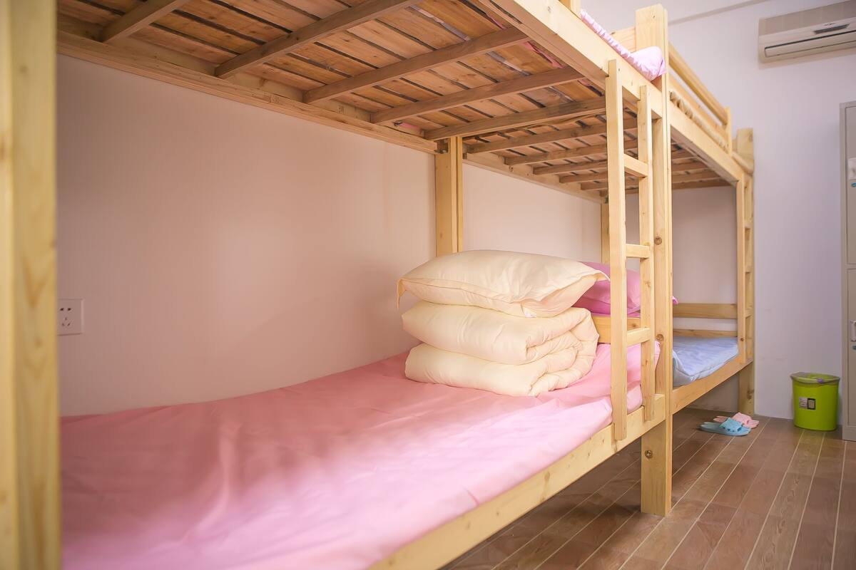 A bunk bed with pink bedding and a wooden headboard.