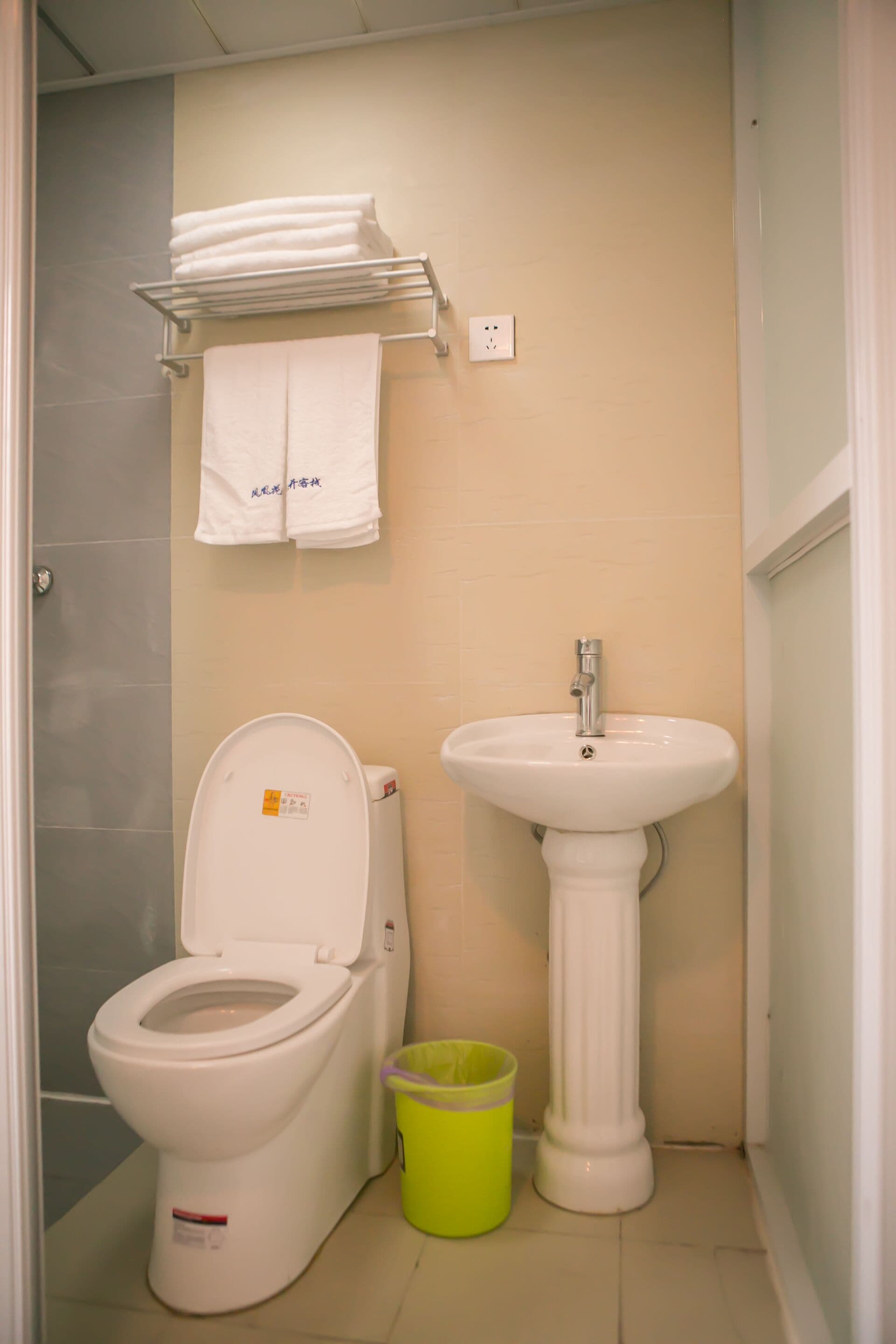A bathroom with a toilet, sink, and a towel rack with folded towels.