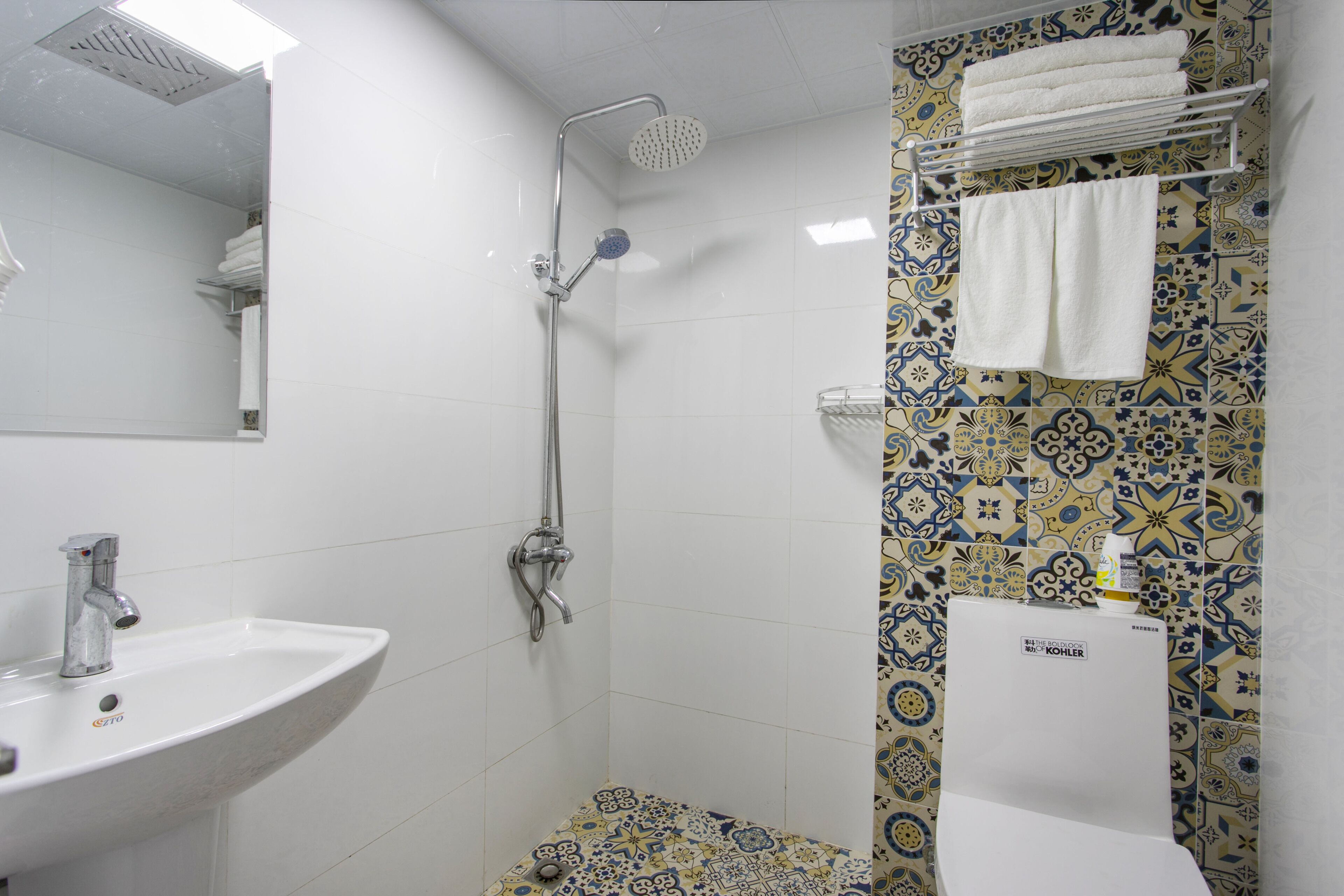 A bathroom with a sink, shower, and patterned tiles.