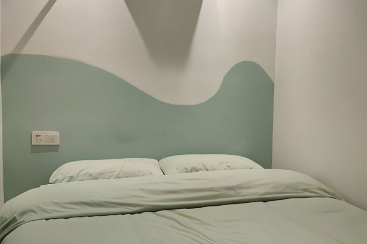 A room with a bed, a wall socket, and a wavy ceiling design.