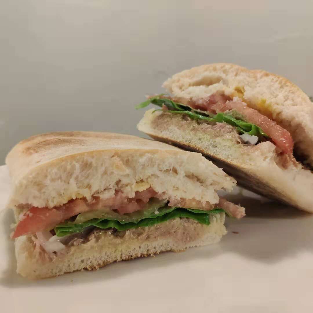 A sandwich cut in half, revealing layers of lettuce, tomato, and meat.