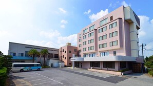 A multi-story hotel with a flat roof, a parking lot, and a bus in the foreground. - Hotel New Otsuka (Shirako)