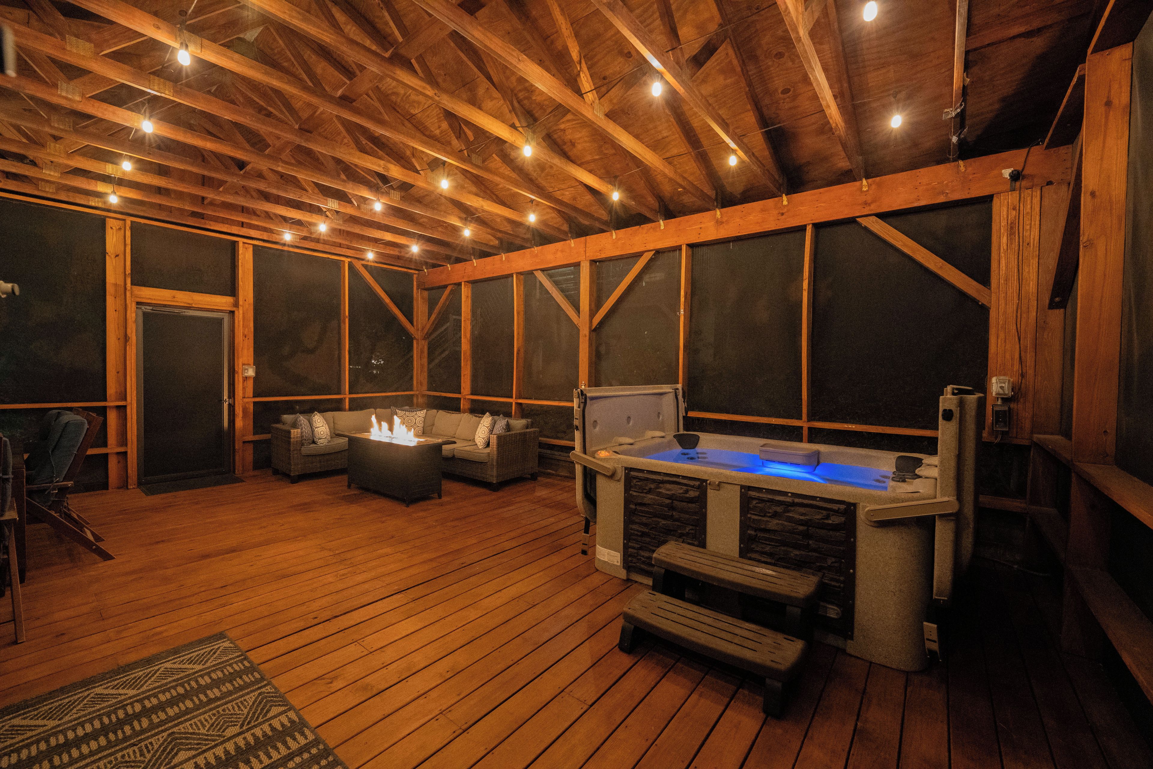 An indoor wooden deck with a hot tub, seating area, and a fireplace.