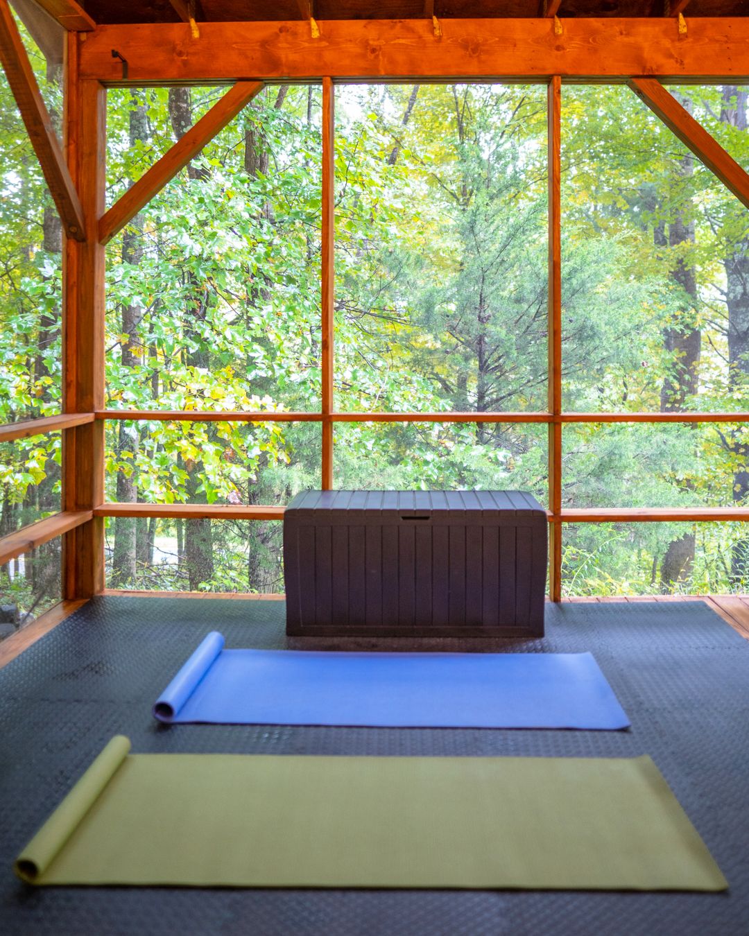 Ein Zimmer mit großem Fenster, Holzbalken und Trainingsmatten.