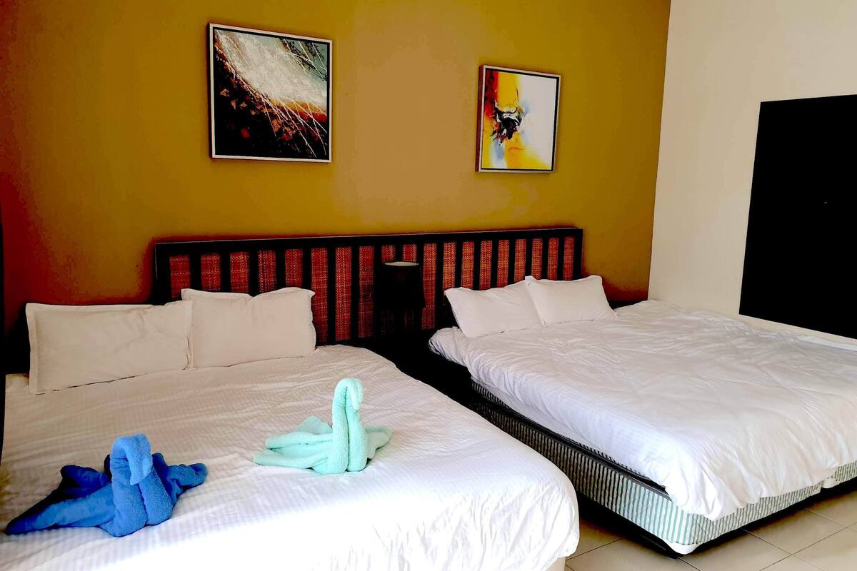 Ein Hotelzimmer mit zwei Betten, einem Kopfteil und zwei Bildern an der Wand.