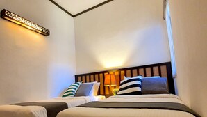 Et hotelværelse med to senge, et natbord med lampe, og en dekorativ væglampe.
