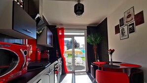 A modern kitchen with red appliances, a dining area with red chairs, and a view of the outside. - The White Home Broadway, Luxury Jacuzzi, exclusive private heated pool  (Châteauroux)