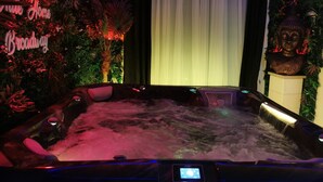 A hot tub with a digital control panel, surrounded by lush greenery and a Buddha statue. - The White Home Broadway, Luxury Jacuzzi, exclusive private heated pool  (Châteauroux)