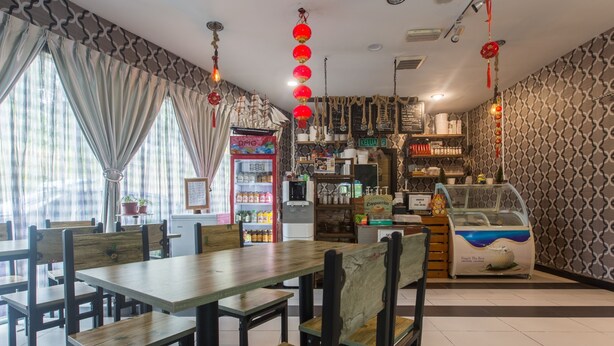 Ein Restaurantinneres mit Holztischen und -stühlen, einem Getränkespender und einer Speisekarte.