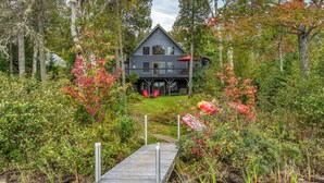 Une cabane à deux étages, dotée d’un porche et d’un quai donnant accès à un petit ruisseau.