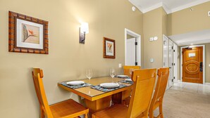 Un coin repas avec une table en bois dressée pour quatre personnes, entourée de chaises en osier.