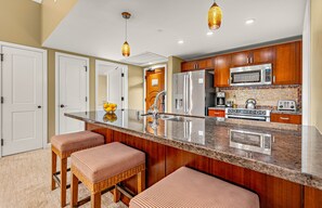 A kitchen with a central island, stainless steel appliances, and wooden cabinets.