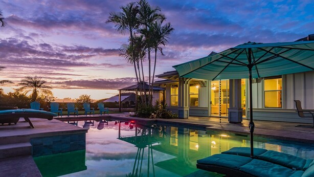 A pool with lounge chairs and an umbrella, surrounded by palm trees and a house with large windows. - 🏖️Private Kona Home w/ Pool, Sand Court & Ocean View Lanai | Nakukui Ekolu (Kailua Kona)