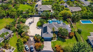 A residential area with multiple houses, a central swimming pool, and a well-maintained lawn. - 🏖️Private Kona Home w/ Pool, Sand Court & Ocean View Lanai | Nakukui Ekolu (Kailua Kona)