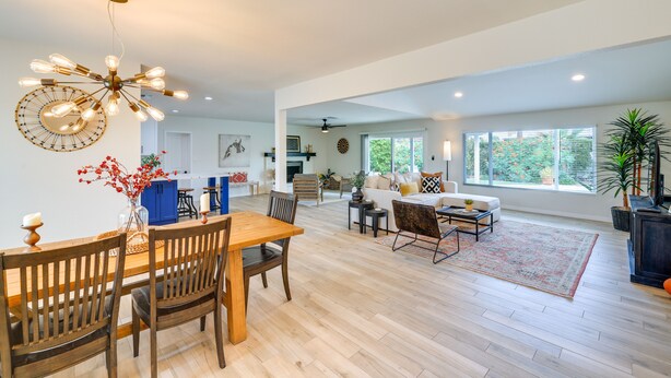 A spacious living area with a wooden dining table, chairs, and a modern chandelier. There is a sofa set and a coffee table in the background. - Near Golfing & Shops: Scottsdale Gem w/ Patio! (Scottsdale)