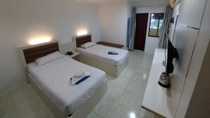 A hotel room with two beds, a desk, a chair, and a minibar. - Penuin Hotel (Batam)