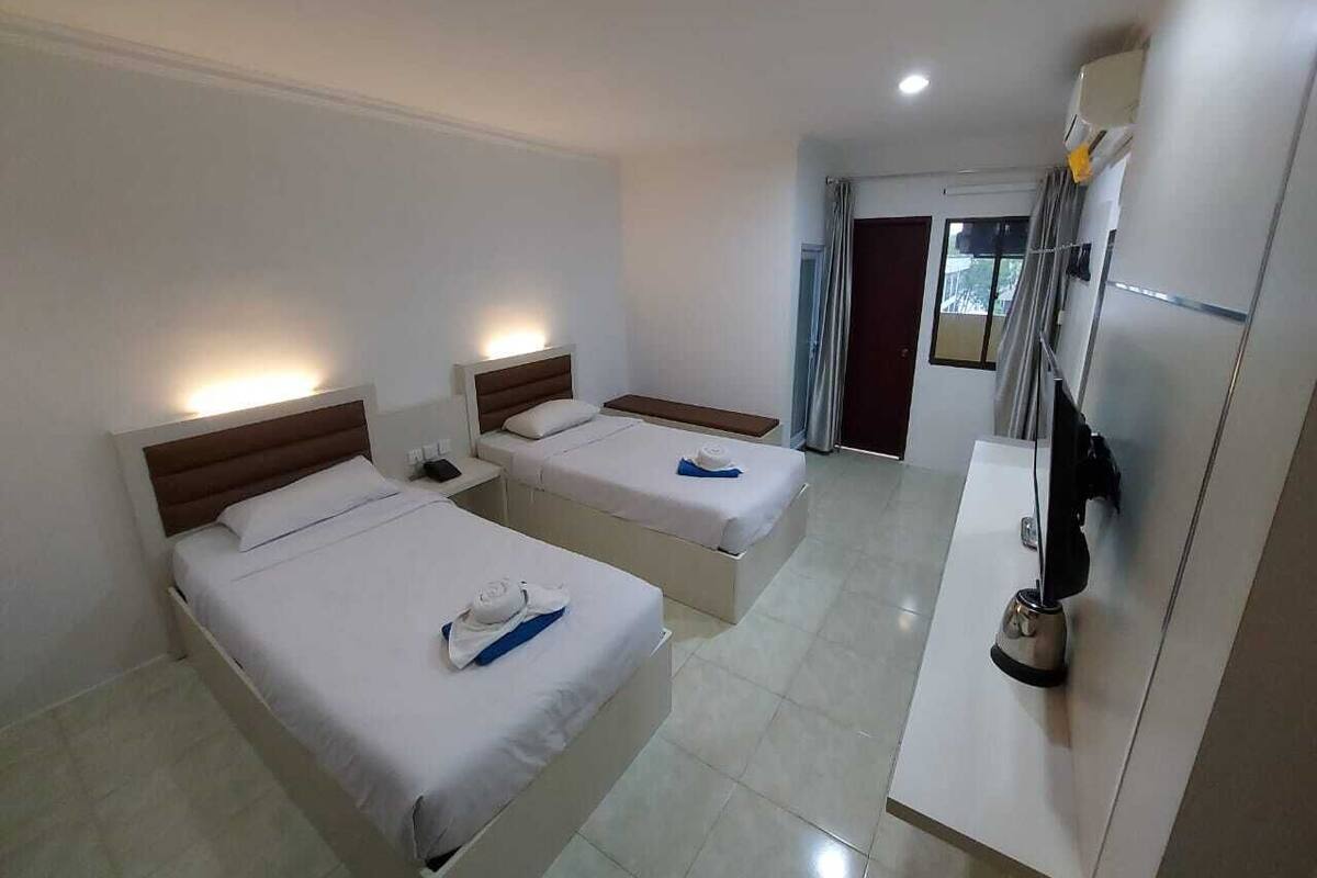 A hotel room with two beds, a desk, a chair, and a minibar.