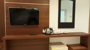 Une chambre d’hôtel équipée d’un téléviseur à écran plat fixé au mur, d’une machine à café posée sur le comptoir et d’un miroir au-dessus du comptoir.